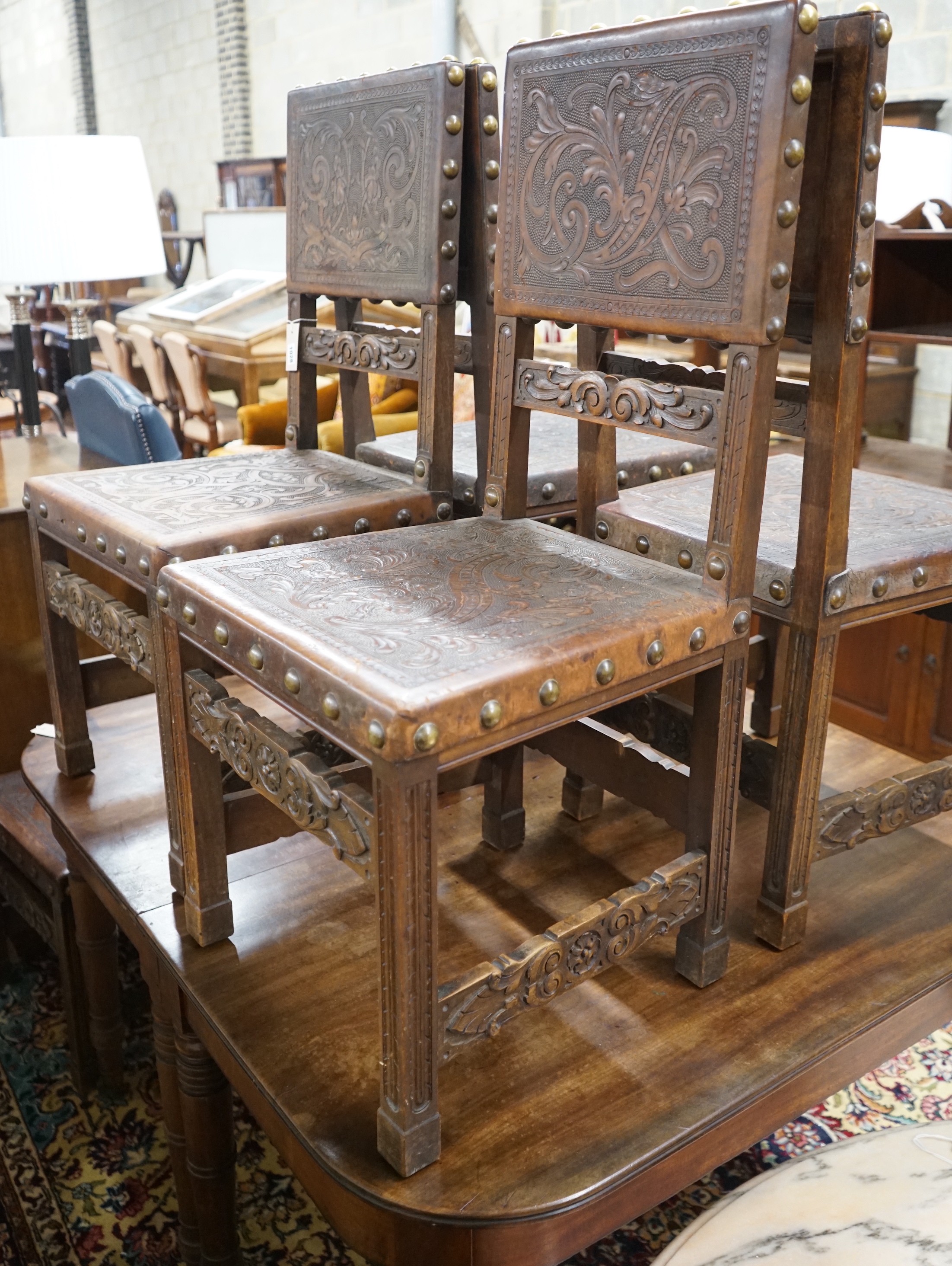 A set of six 18th century style brass studded carved oak and embossed leather dining chairs